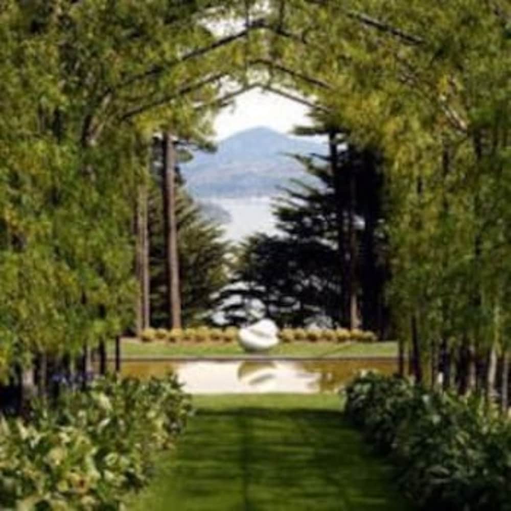 A serene garden pathway framed by lush greenery leads to a tranquil pond reflecting a distant mountain, ideal for nature lovers seeking peaceful retreats.