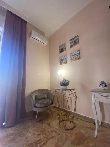 A cozy corner in a warmly lit apartment features a stylish armchair, decorative side tables, and framed artwork, creating an inviting atmosphere ideal for travelers seeking comfort and charm.