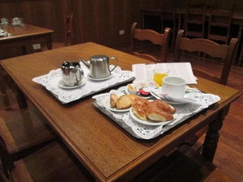 A cozy breakfast scene featuring pastries, coffee, and juice on a wooden table in a rustic dining room, ideal for travelers seeking a warm and inviting start to their day.
