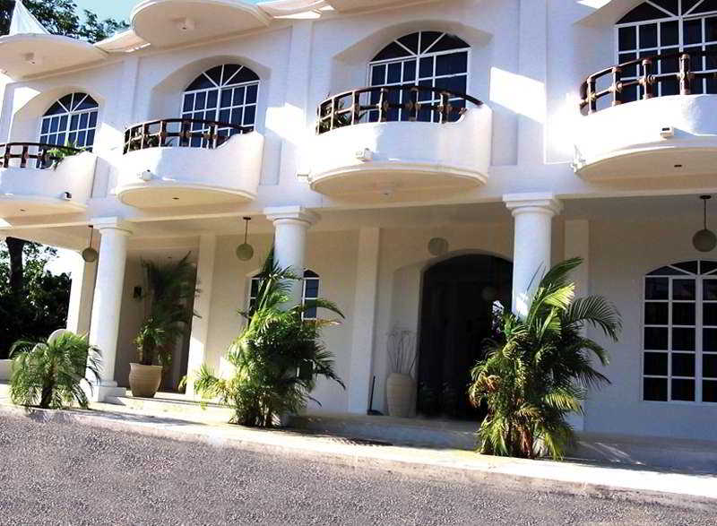 A luxurious white villa with elegant balconies and tropical plants exudes a serene and inviting atmosphere, perfect for a high-end vacation rental or resort stay.