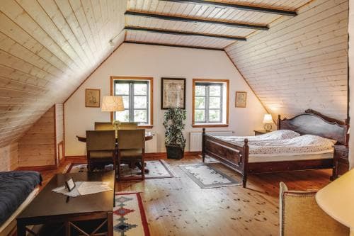 A cozy attic bedroom with wooden beams, warm lighting, and rustic furniture creates an inviting atmosphere, perfect for travelers seeking a charming and comfortable retreat.