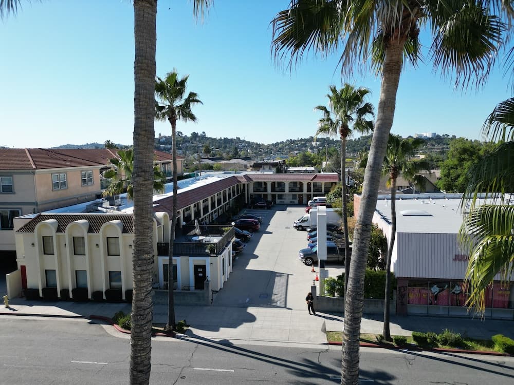 A sunny day in a suburban area features palm trees lining a street near a motel complex, creating a relaxed atmosphere ideal for travelers seeking a warm-weather getaway.