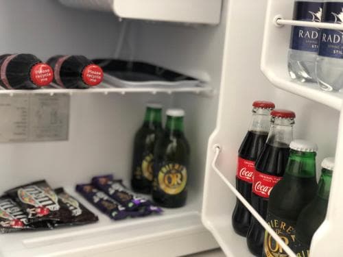 A cozy hotel minibar scene featuring a mix of beverages like Coca-Cola, beer bottles, and snacks, creating a relaxed and convenient atmosphere for travelers seeking refreshments.