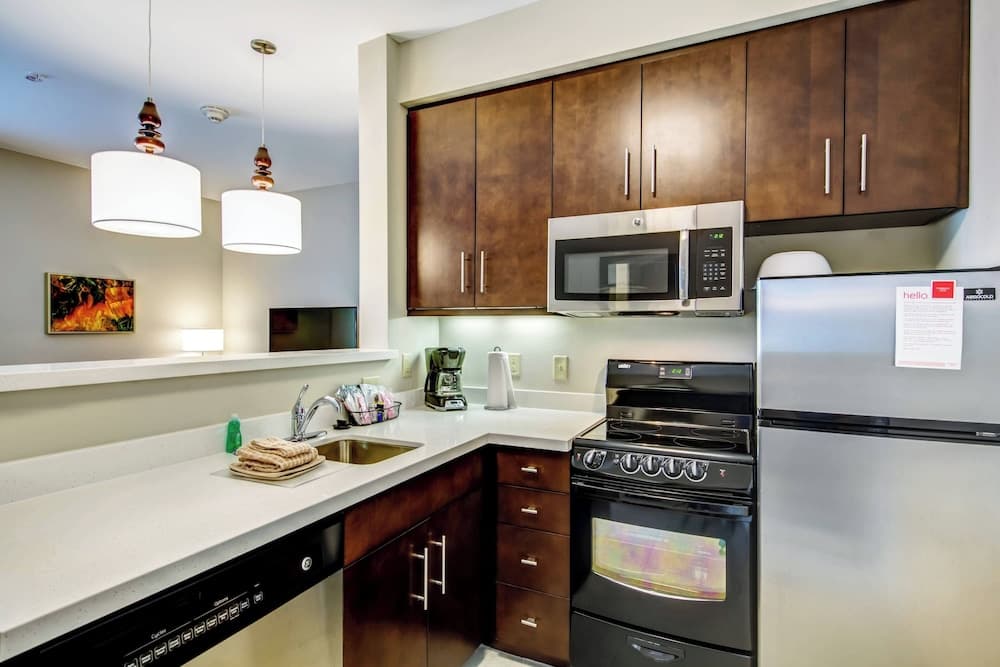 A cozy apartment kitchen featuring sleek stainless steel appliances, warm wooden cabinets, and modern pendant lights, ideal for travelers seeking a homey cooking experience during their stay.