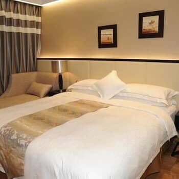 A cozy hotel room features neatly arranged beds with plush bedding, framed artwork on the walls, and soft lighting, creating a serene atmosphere ideal for travelers seeking relaxation.