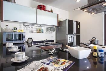 A sleek, modern kitchen with stainless steel appliances, a glossy black countertop, and organized utensils creates an inviting atmosphere ideal for culinary enthusiasts seeking inspiration for their next cooking adventure.
