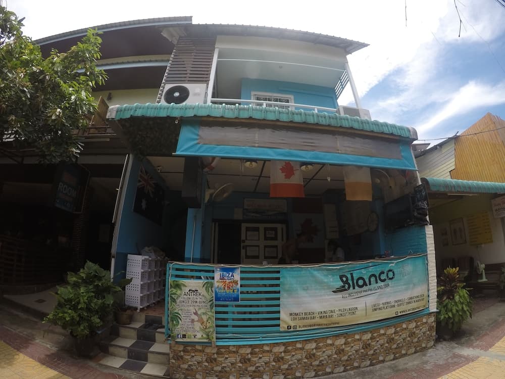 A vibrant blue storefront adorned with travel posters and flags invites travelers to explore tours in a tropical setting, perfect for adventure seekers looking for local experiences.