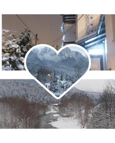 A serene winter landscape featuring snow-covered trees and mountains framed by a heart-shaped cutout, set against the backdrop of a cozy village inn, evokes a romantic and tranquil mood ideal for a winter getaway.