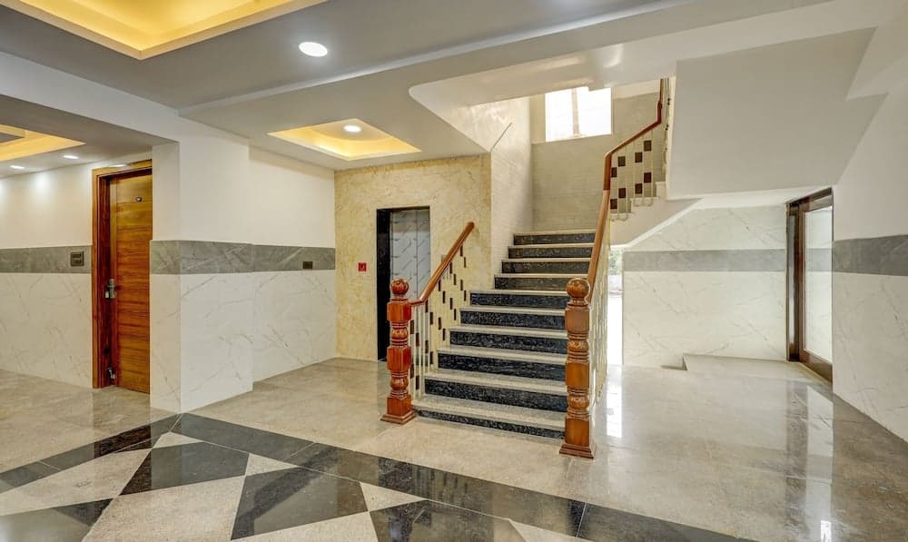 A luxurious hotel lobby features a grand staircase with marble steps, ornate wooden railings, and polished floors, creating an elegant atmosphere ideal for travelers seeking upscale accommodations.