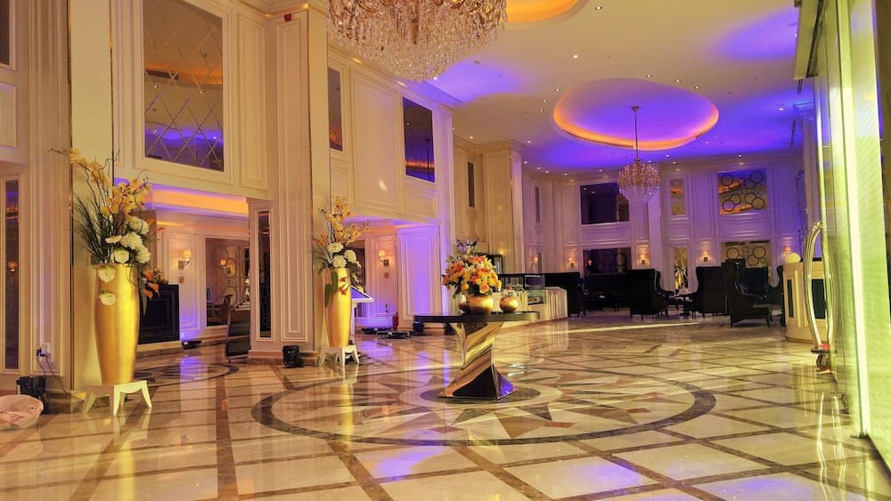A luxurious hotel lobby dazzles with its opulent marble floors, grand chandeliers, vibrant floral arrangements, and ambient lighting, ideal for travelers seeking a premium accommodation experience.