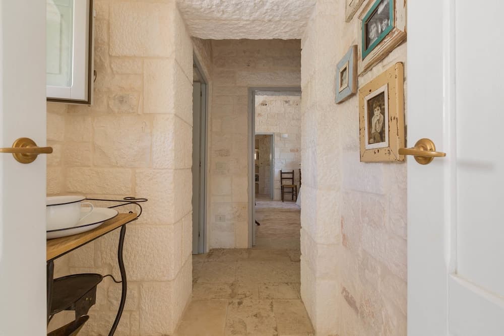 A cozy stone-walled hallway adorned with rustic frames and warm lighting creates an inviting atmosphere, perfect for exploring charming countryside accommodations.