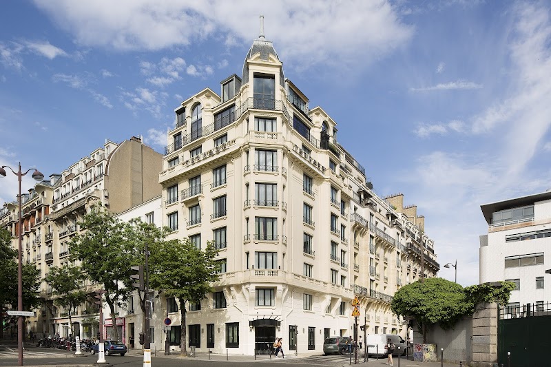 A charming Parisian hotel with elegant balconies and a classic facade stands invitingly on a sunny day, perfect for travelers seeking a stylish urban retreat in the heart of the city.