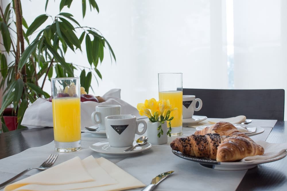 A cozy breakfast setting with croissants, orange juice, and fresh flowers on a neatly arranged table by a window, ideal for a relaxing morning getaway at a boutique hotel.