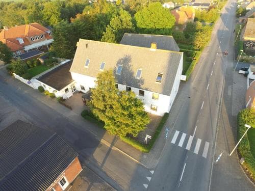 An aerial view captures a quaint suburban neighborhood with charming houses, lush greenery, and a peaceful street lined with trees, ideal for travelers seeking a serene residential retreat.