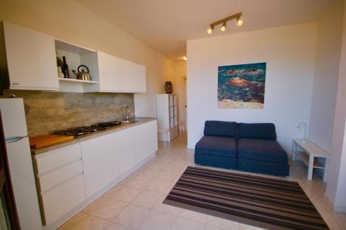 A cozy apartment interior features a modern kitchenette, a comfortable blue sofa, and vibrant wall art, creating an inviting atmosphere ideal for short-term rentals or vacation stays.