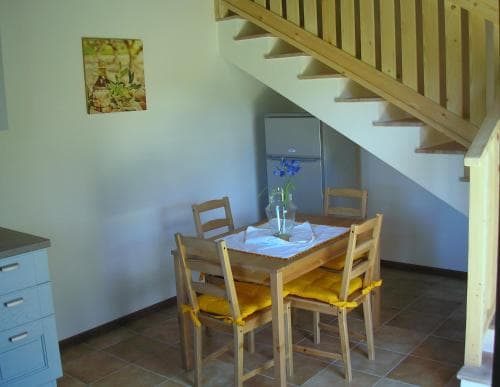 A cozy dining nook with wooden furniture and yellow cushions sits beneath a staircase in a quaint vacation rental, perfect for travelers seeking a charming and functional space.