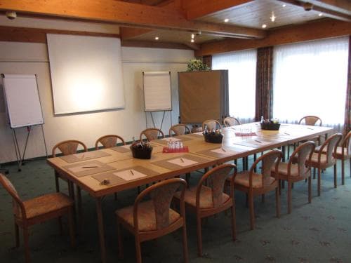 A cozy conference room with wooden tables, chairs, flip charts, and large windows offers an ideal setting for professional meetings or workshops.