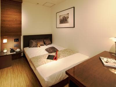A cozy hotel room features a neatly made bed with plush pillows, wooden furnishings, and soft lighting, creating a serene atmosphere ideal for travelers seeking relaxation.