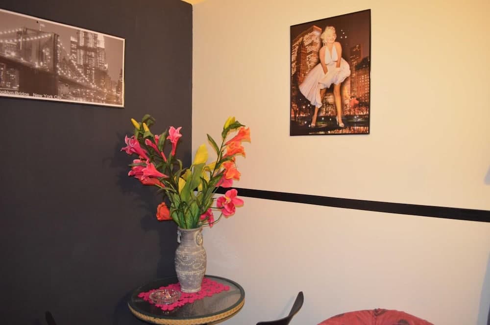 A cozy corner adorned with vibrant flowers in a vase, Marilyn Monroe and Brooklyn Bridge posters, exudes a nostalgic charm ideal for travelers seeking a personalized and artistic accommodation experience.