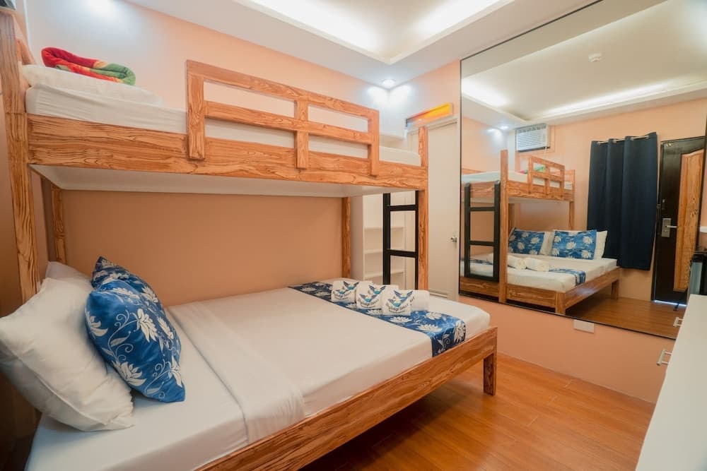 A cozy hostel room with wooden bunk beds adorned with blue floral pillows, warm peach walls, and a large mirror, ideal for budget travelers seeking comfort and style.