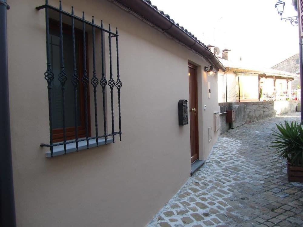 A serene cobblestone alleyway lined with rustic buildings featuring ornate iron window bars and wooden doors evokes a quaint European village charm, perfect for travelers seeking a peaceful retreat.