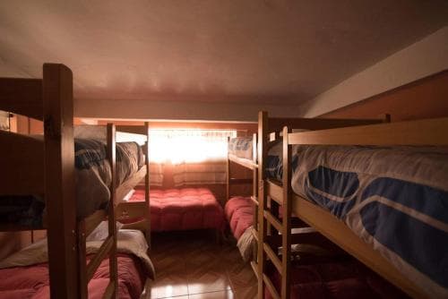 A cozy hostel room with wooden bunk beds, soft lighting, and a warm ambiance, ideal for budget travelers seeking comfortable accommodation.