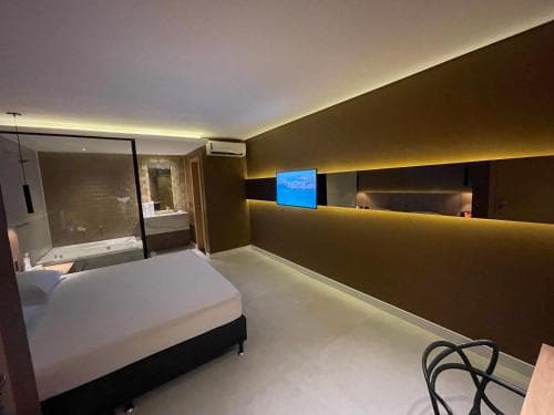 A modern hotel room features a cozy bed, sleek bathroom with a bathtub, ambient lighting, and a mounted TV, creating a serene atmosphere ideal for travelers seeking comfort and relaxation.