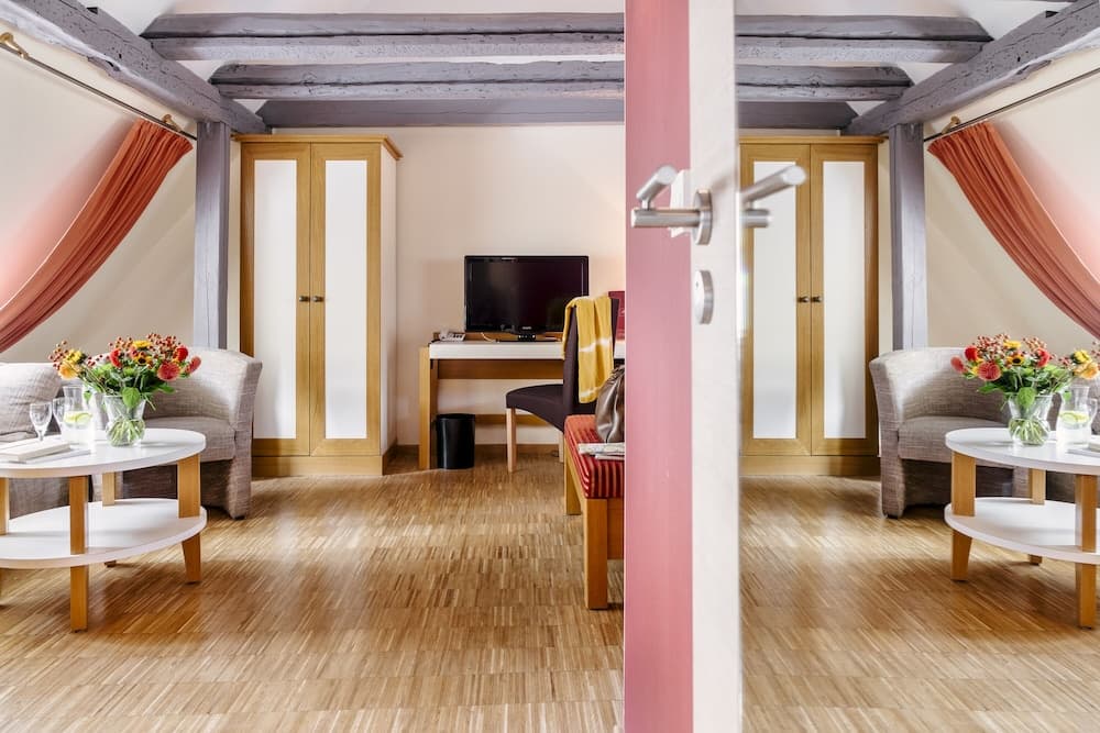 A cozy attic-style hotel room with wooden beams, warm lighting, and vibrant floral arrangements creates an inviting atmosphere perfect for travelers seeking comfort and charm.