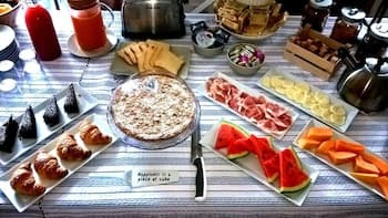 A cozy indoor dining setup features an array of fresh fruits, sushi rolls, and a central dish on a checkered tablecloth, ideal for a relaxed brunch or casual gathering.