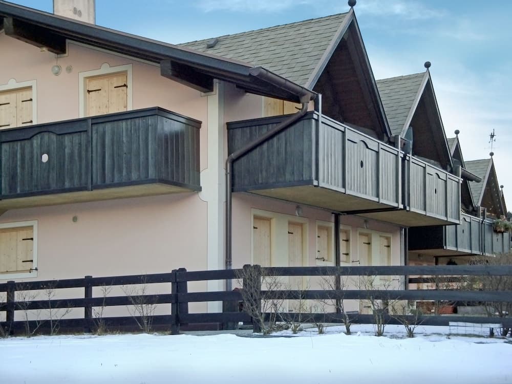 A serene winter scene showcases quaint alpine chalets with wooden balconies and snow-covered grounds, ideal for a cozy ski resort getaway.