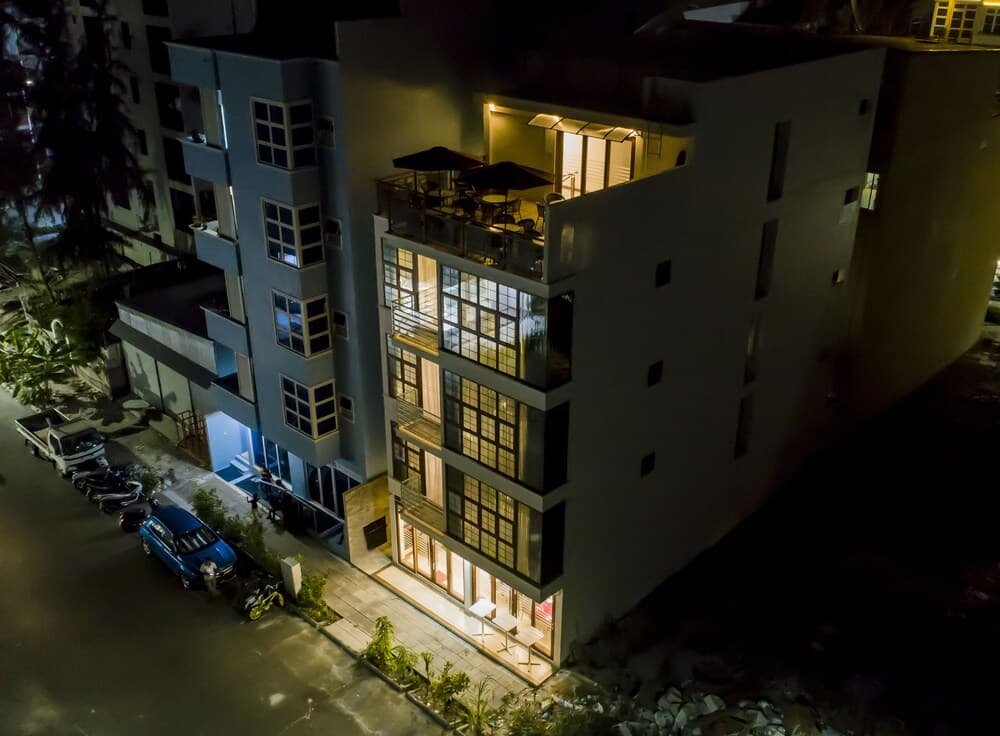 A cozy urban apartment complex illuminated at night features balconies with outdoor seating, creating an inviting atmosphere ideal for city travelers seeking a comfortable stay.
