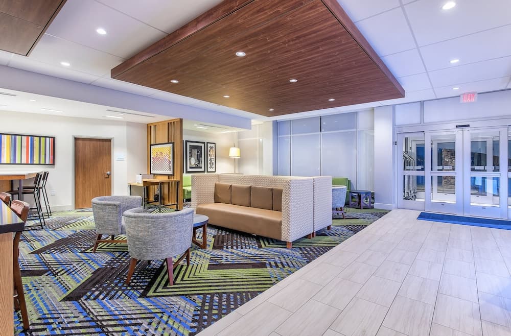 A modern hotel lobby features a cozy seating area with patterned carpets, contemporary furniture, and large windows, creating a welcoming atmosphere ideal for travelers seeking comfort and style during their stay.