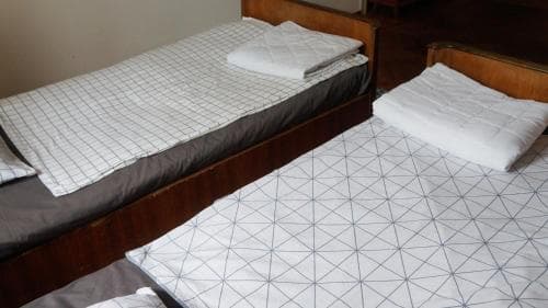 A cozy hostel room features two neatly made beds with geometric-patterned linens, creating a simple and inviting atmosphere ideal for budget travelers seeking comfortable accommodations.