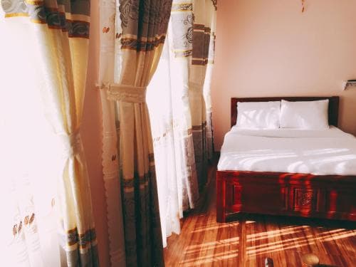A cozy hotel room with warm sunlight streaming through patterned curtains onto a neatly made bed, ideal for travelers seeking comfort and relaxation.