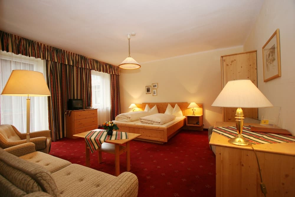 A cozy hotel room features warm wooden furnishings, plush seating, and soft lighting, creating an inviting atmosphere ideal for travelers seeking comfort and relaxation.