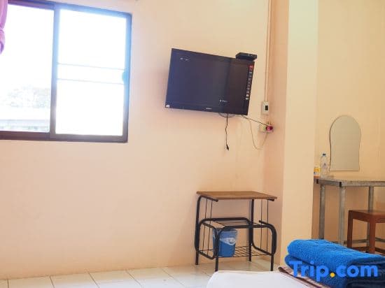 A cozy budget hotel room features a wall-mounted TV, simple furniture, and natural light from a window, ideal for travelers seeking affordable accommodations.