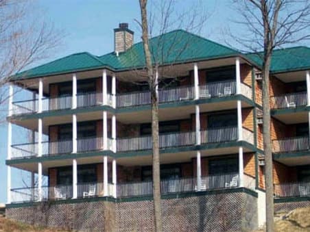 A serene multi-story lodge with balconies nestled among bare trees offers a tranquil retreat for travelers seeking a cozy getaway in a natural setting.