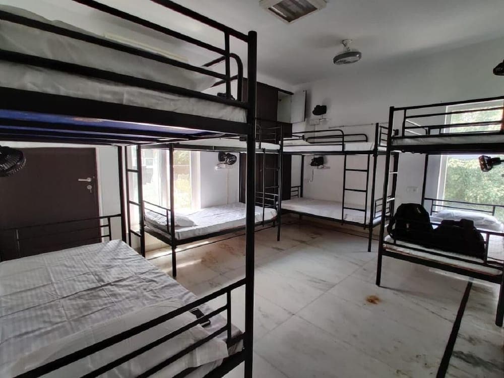 A cozy hostel room with metal bunk beds, tiled floors, and large windows offers a budget-friendly accommodation option for travelers seeking simplicity and comfort.