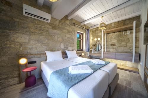 A cozy hotel room with rustic stone walls, modern furnishings, and warm lighting creates an inviting atmosphere perfect for travelers seeking comfort and relaxation.