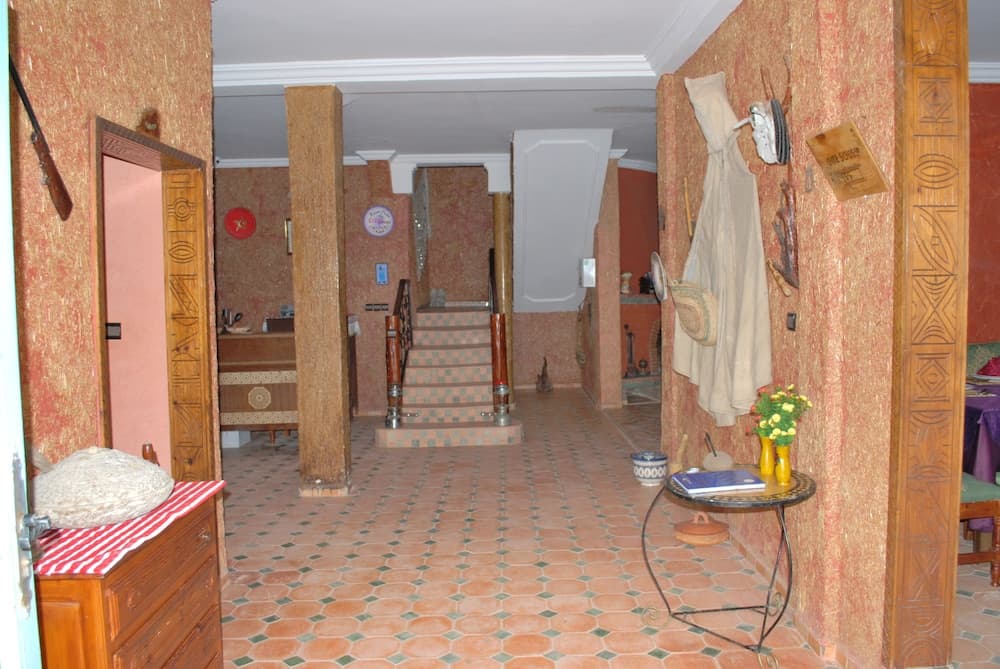 A warmly lit, rustic interior hallway with terracotta-tiled floors, wooden pillars, and eclectic decor creates an inviting atmosphere ideal for travelers seeking a cozy, culturally rich accommodation experience.