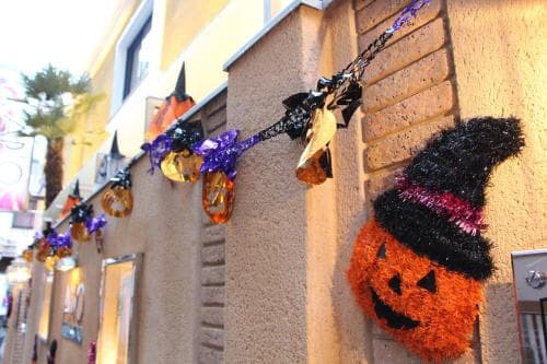 A festive urban street scene adorned with Halloween decorations like jack-o'-lanterns and witch hats creates a spooky yet cheerful atmosphere, perfect for seasonal travel photography.