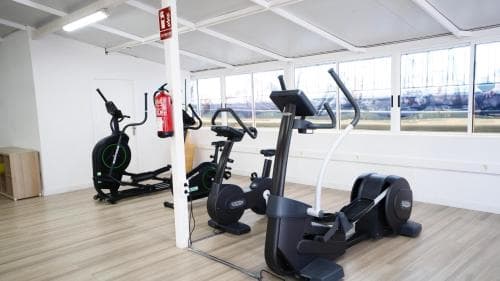 A bright, modern gym space features cardio machines like ellipticals and exercise bikes near large windows, creating an inviting atmosphere ideal for travelers seeking fitness facilities during their stay.