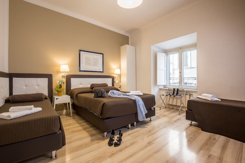 A cozy hotel room with two neatly made beds, soft lighting, and a window view, exudes warmth and comfort, ideal for travelers seeking relaxation and convenience.