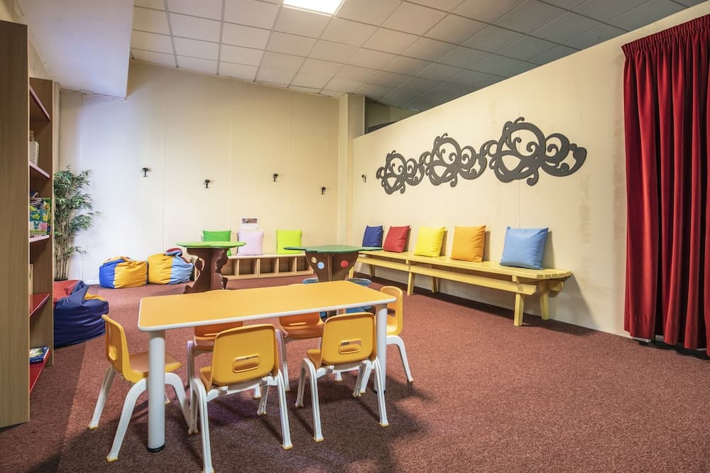 A vibrant children's playroom features colorful furniture, bean bags, and decorative pillows against beige walls, creating a cheerful and inviting atmosphere ideal for family-friendly accommodations or daycare centers.