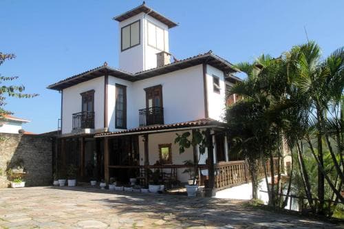 A charming two-story villa with wooden balconies and lush tropical foliage invites travelers to a serene retreat, perfect for a relaxing vacation getaway.