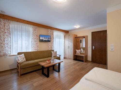 A cozy hotel room with wooden accents, floral curtains, and a comfortable seating area offers a serene retreat for travelers seeking relaxation.