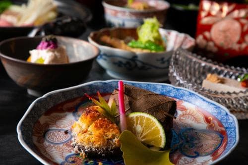 A cozy dining scene featuring an array of colorful Japanese dishes on ornate plates, evoking a warm, cultural culinary experience ideal for food enthusiasts exploring traditional cuisine.