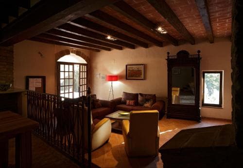 A cozy living room with rustic wooden beams, warm lighting, and comfortable seating creates an inviting atmosphere ideal for travelers seeking relaxation in a charming, historic accommodation.