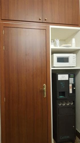 A cozy hotel room corner features a wooden cabinet, microwave, coffee machine, and neatly arranged amenities, creating a welcoming atmosphere for travelers seeking convenience and comfort.