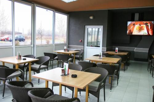 A cozy indoor café with wooden tables, black chairs, and large windows offering a view of parked cars outside, creates a relaxed atmosphere ideal for travelers seeking a quiet spot to dine or work.